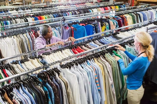 Retail employees in a clothing store filled with garments, illustrating inventory turnover, stockouts, and the need for accurate inventory management.