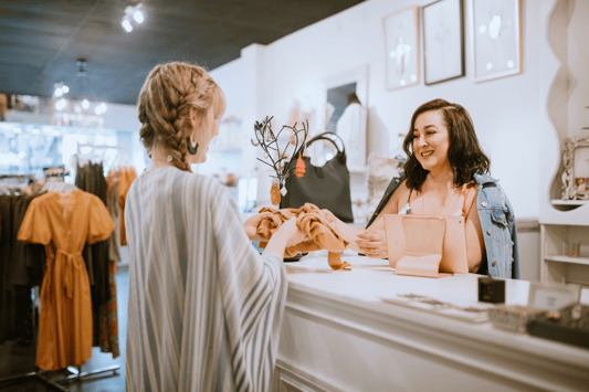 Retail associate and customer at a checkout counter, engaging in a product exchange, symbolizing the connection between customer demand and efficient inventory planning in retail environments.