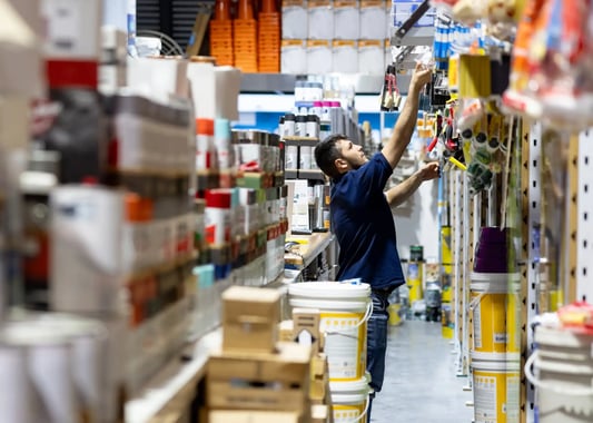 Retail clerk managing stock with AI-powered automated replenishment system.