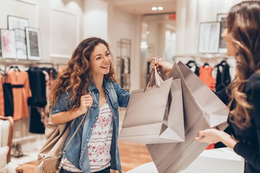 Happy girl shopping in a fashion store, selecting clothing items with enthusiasm.