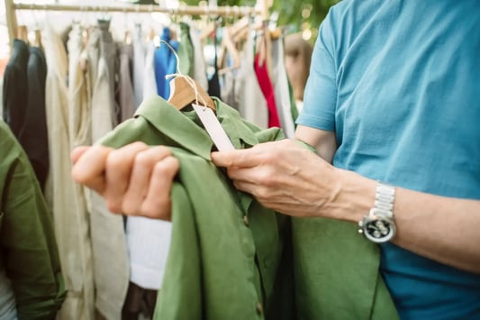 Man checking the price of a green button up shirt.
