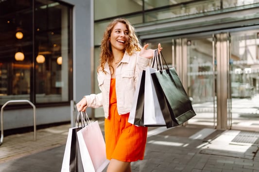 Cheerful woman shopping with multiple bags, illustrating the importance of retail as a service.