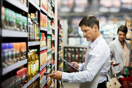 Store worker scanning products for real-time inventory optimization.