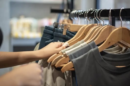 Customer browsing clothing racks in a retail store, highlighting merchandise availability and inventory management.