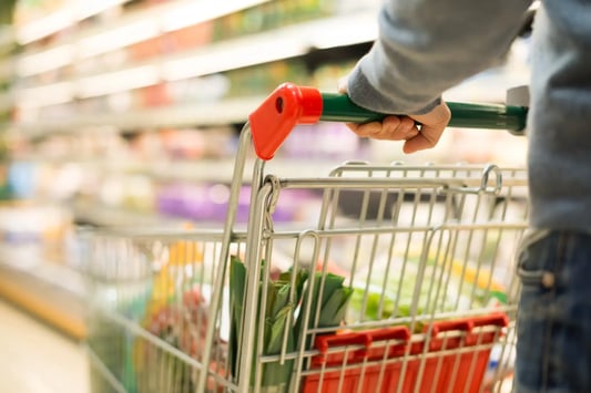 Supermarket employee in apron managing shelf inventory and replenishment as part of retail operations to reduce spoilage and improve stock rotation.