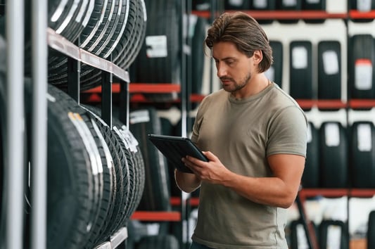 Retail worker checking inventory in tire store.