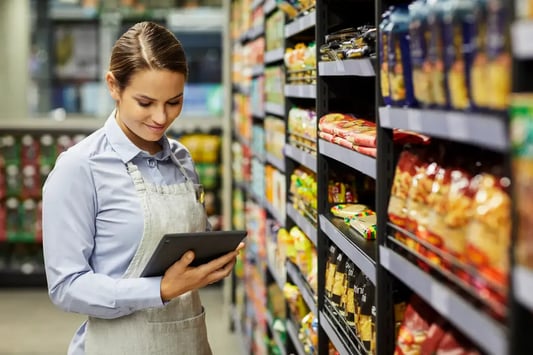 Grocery store employee reviewing planogram compliance on a tablet.