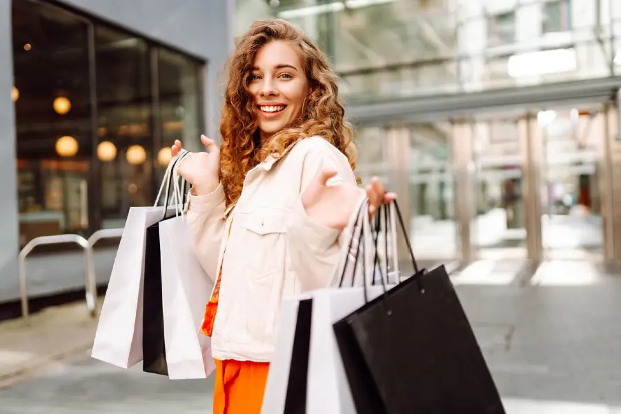 A shopper carrying multiple bags outdoors, representing consumer behavior shifts and 2026 retail industry outlook trends.