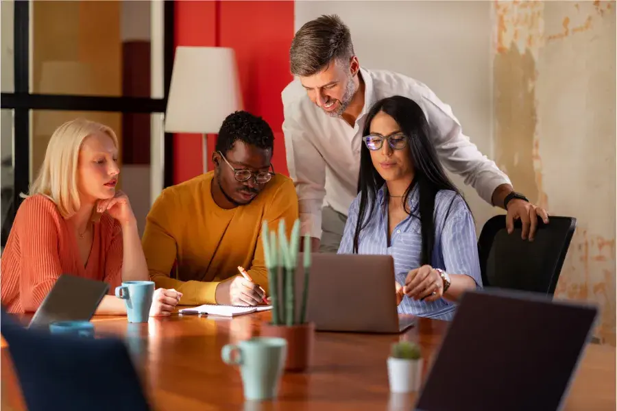 Team collaborating on laptops and notes, illustrating assortment planning, product mix optimization, merchandising strategy, and retail analytics for customer-driven product assortment decisions.