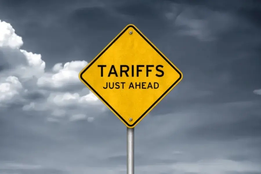 A yellow road sign reading 'Tariffs Just Ahead' against a cloudy sky, symbolizing the impact of tariffs and inflation on retail pricing.
