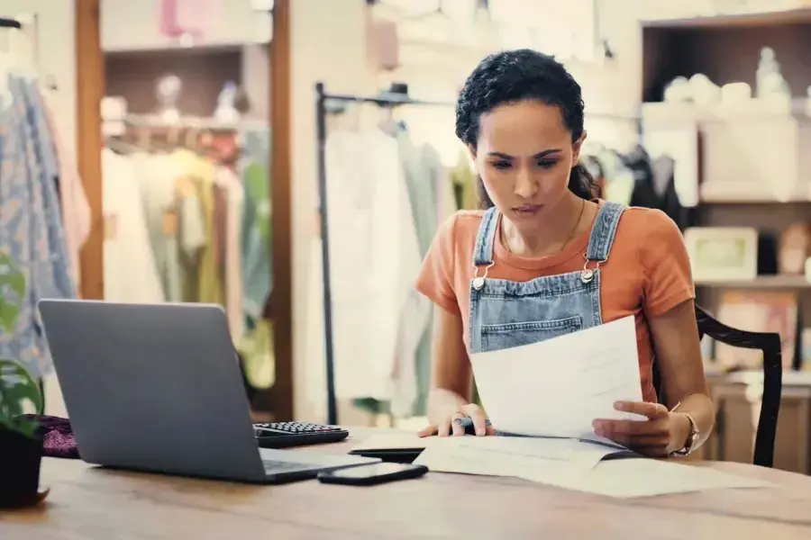 Business owner analyzing retail pricing data and financial reports to optimize inventory and revenue with AI solutions.