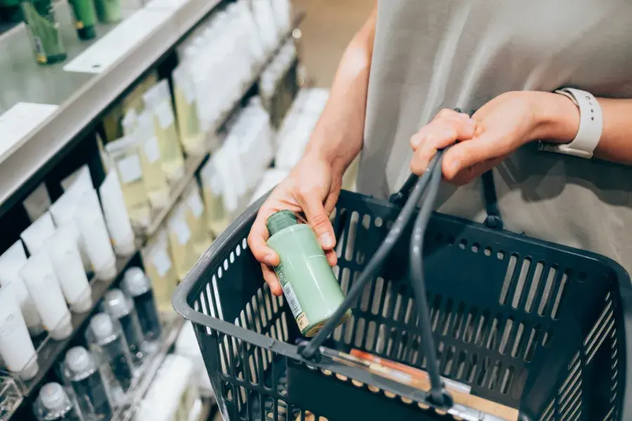 Shopper holding a product in a basket at a retail store, symbolizing retail life cycles from product introduction to maturity, customer loyalty, inventory management, and strategic growth.