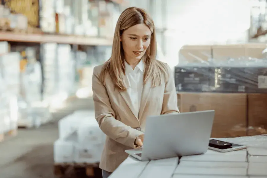 A professional working on a laptop in a retail warehouse, symbolizing AI-powered inventory optimization solutions — balancing stock levels, reducing overstock, and enhancing supply chain efficiency.