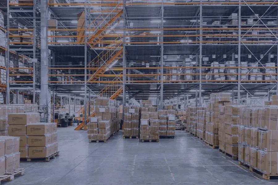 Rows upon rows of pallets filled with boxes in a large warehouse, depicting the problem of excess inventory. This image highlights the need for robust inventory planning software to track stock levels in real-time, optimize inventory across multiple locations, and avoid the financial strain of overstocking.