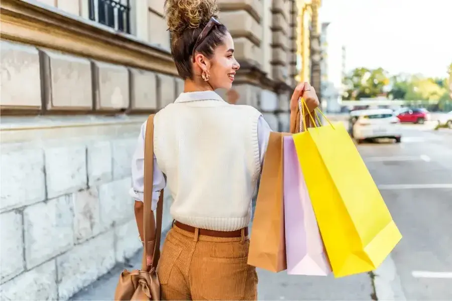 Happy shopper walking outside with colorful shopping bags, reflecting customer loyalty and retail experience