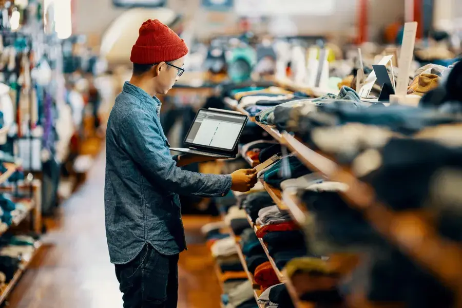 Retail employee using a tablet to track inventory costs and improve inventory visibility with modern inventory management systems.
