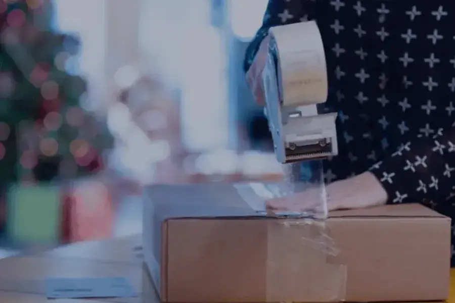 A person sealing a returned package with packing tape during the holiday returns season