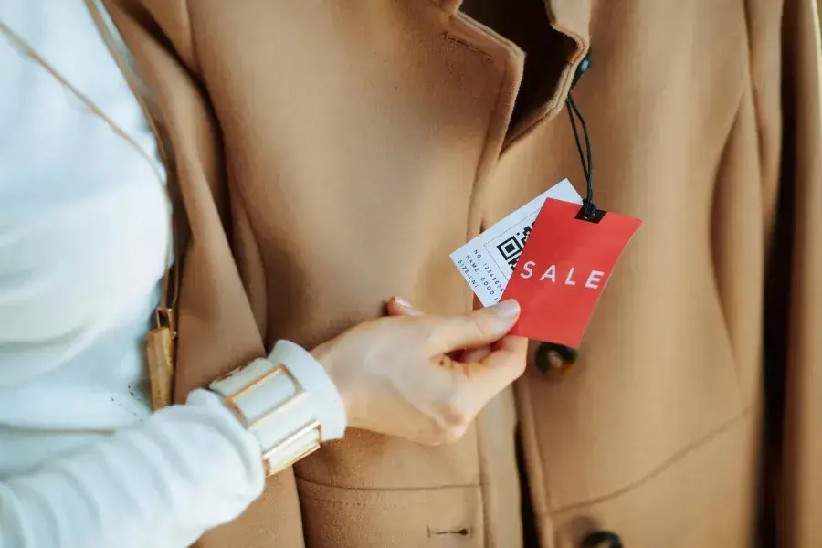 Woman shopping in a boutique, highlighting promotional pricing tactics like flash sales, seasonal discounts, and loyalty offers.
