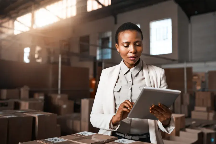 Warehouse manager using a tablet to oversee inventory and logistics, illustrating retail scalability through efficient supply chain management, automation, and adaptive retail operations.