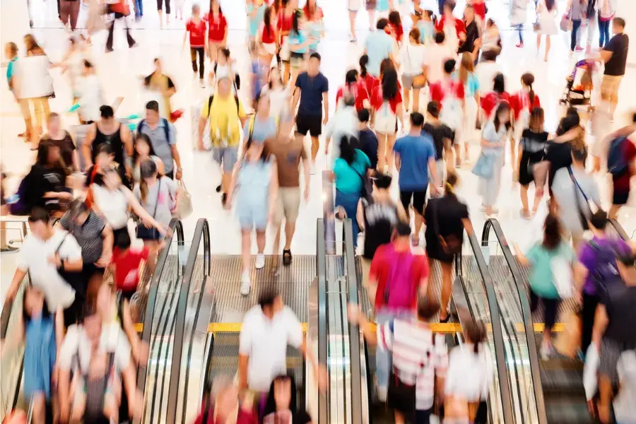 Crowded shopping mall with shoppers using escalators, symbolizing the scale of returns challenges and the role of Retail AI and AI decisioning in managing them.