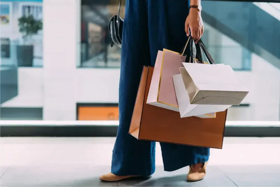 Woman holding shopping bags symbolizing competitive retail pricing strategies and customer behavior.