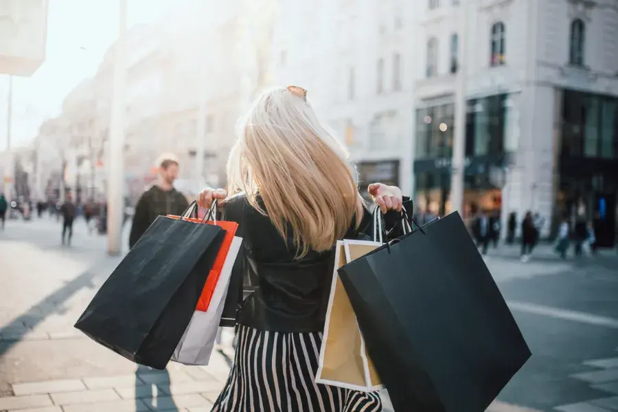 A woman carrying multiple shopping bags on a busy city street, illustrating retail decisions influenced by fraud prevention, payment processing, ecommerce solutions, automation, and risk management to enhance customer experience and business operations.