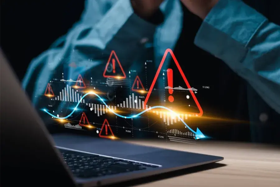 A stressed professional views fluctuating charts and warning symbols on a laptop, representing challenges in retail forecast accuracy, including forecast errors, demand planning issues, and the need for accurate forecasting methods powered by machine learning.