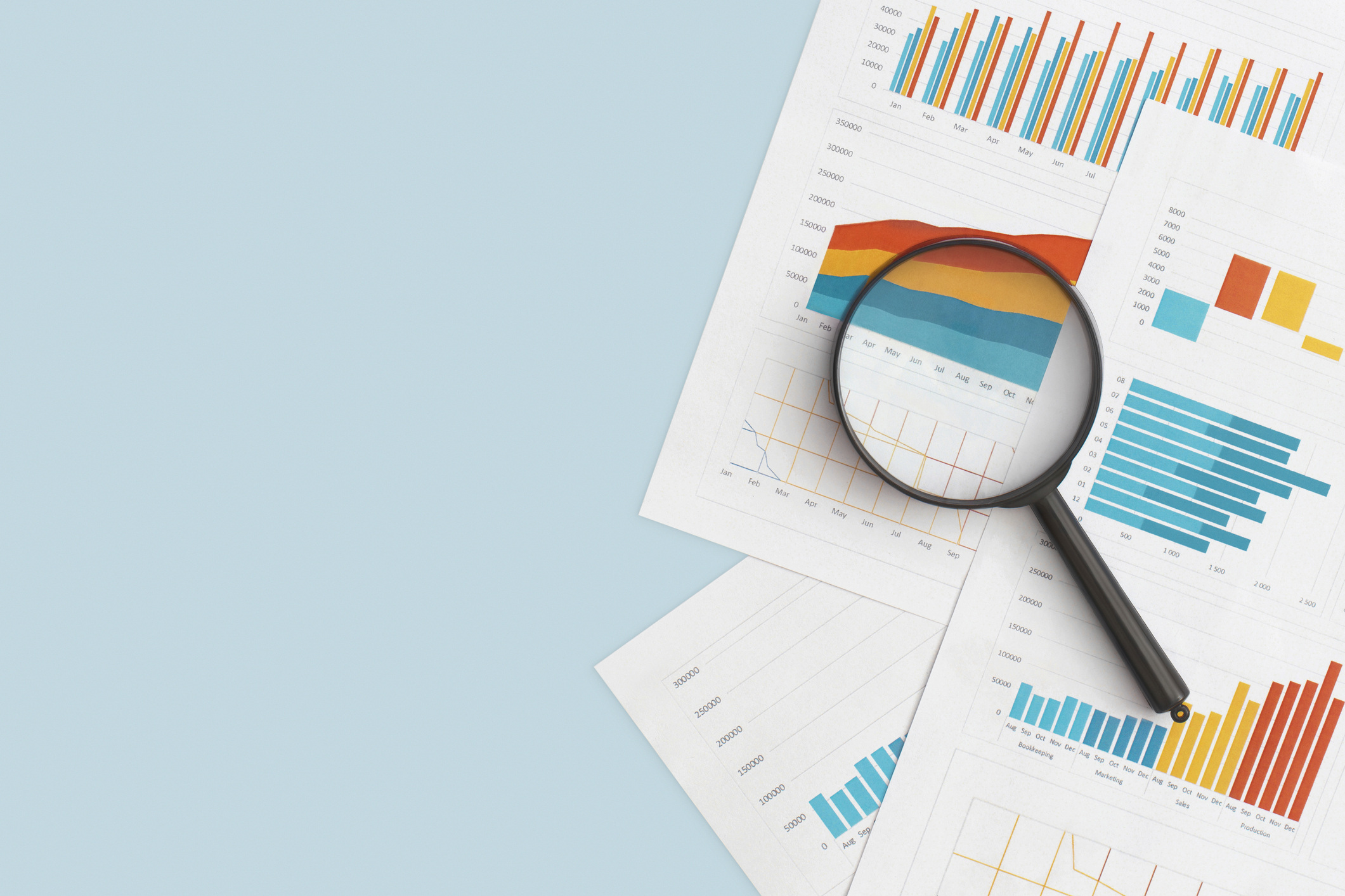 Magnifying glass over charts and graphs representing data analysis for retail merchandise planning, forecasting, and performance tracking