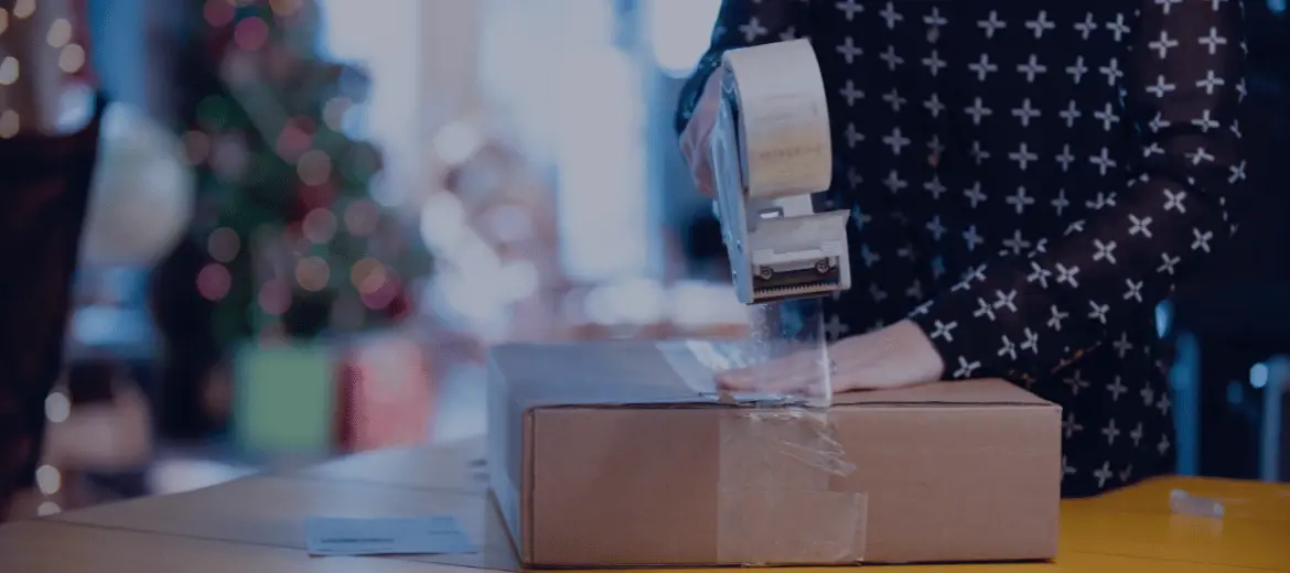 A person sealing a returned package with packing tape during the holiday returns season