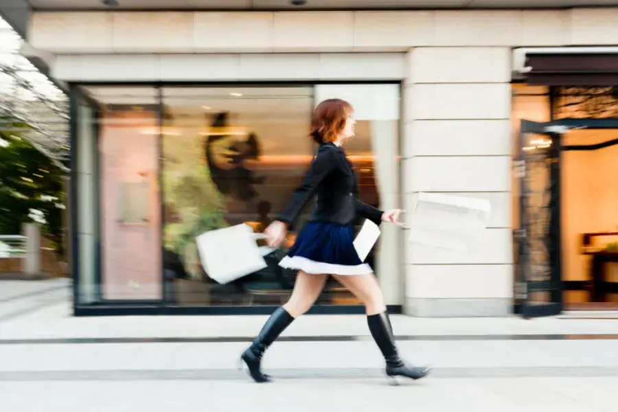 a shopper carrying bags outside a retail store, symbolizing efficiency and optimized inventory management in modern retail