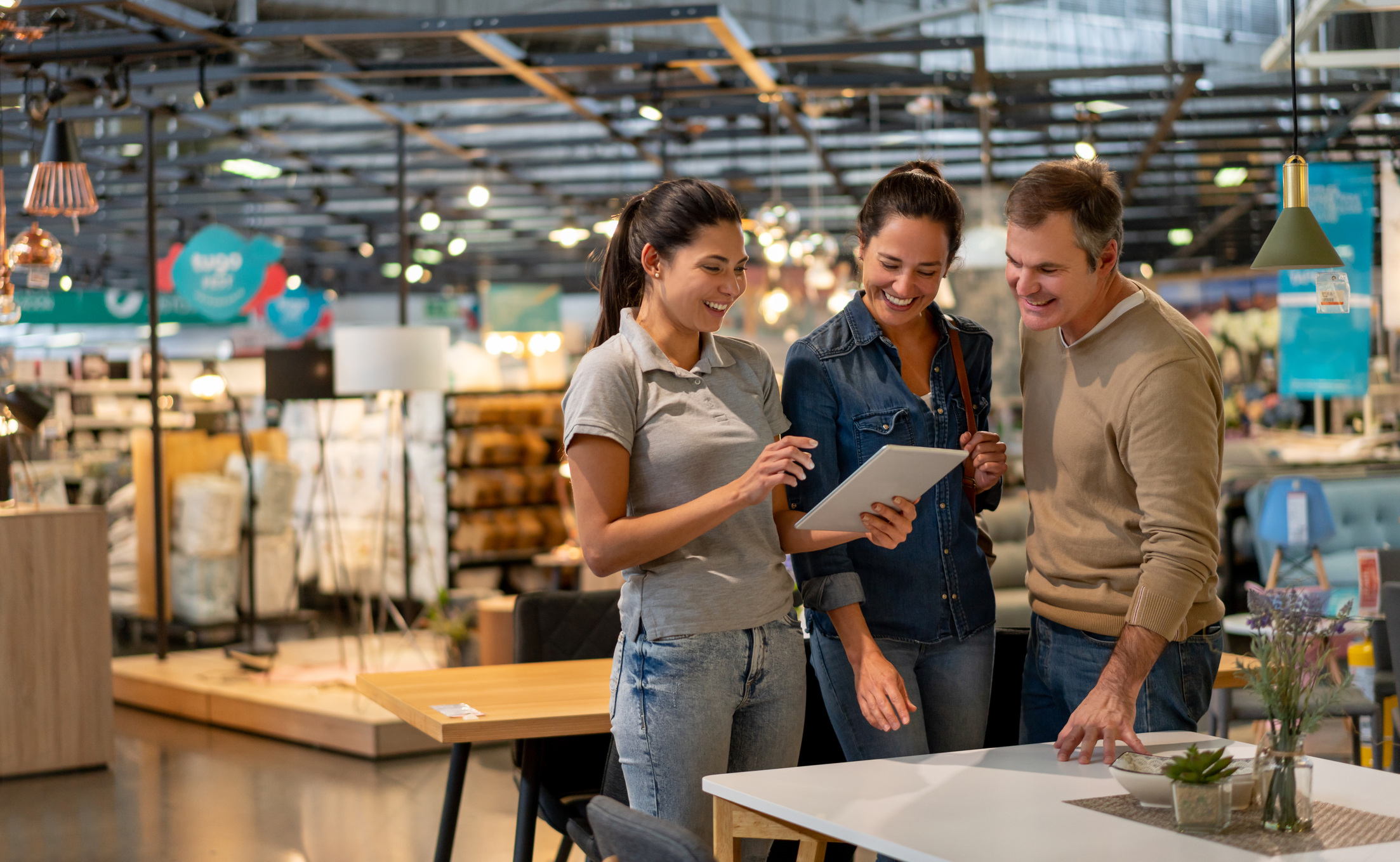 Three people in a modern retail store discussing inventory management while looking at a tablet. The setting reflects omnichannel trends in retail operations.