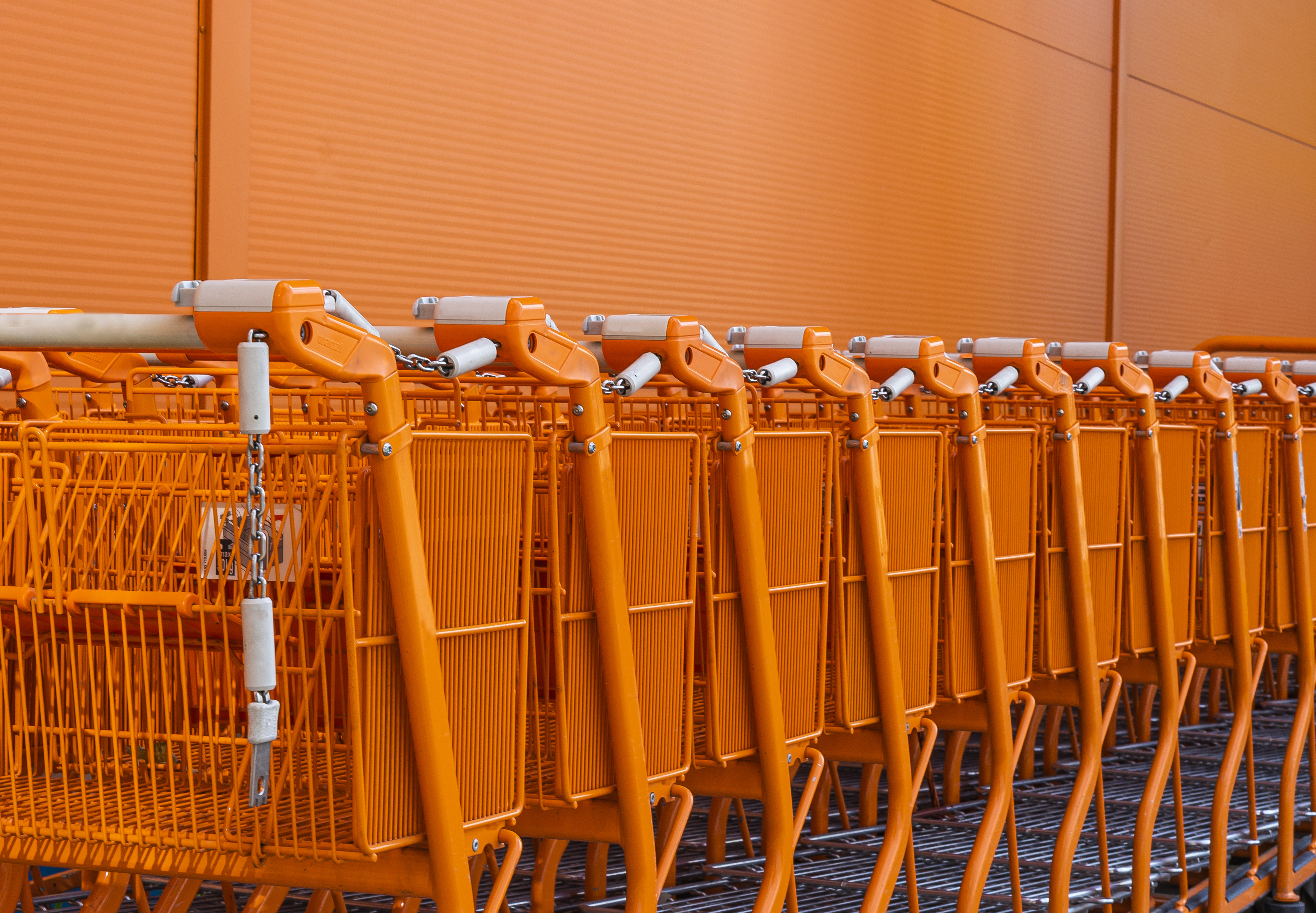 A row of orange shopping carts symbolizes inventory analytics, helping inventory managers track inventory levels, optimize stock levels, and use ABC analysis and VED analysis for effective inventory management in the supply chain.