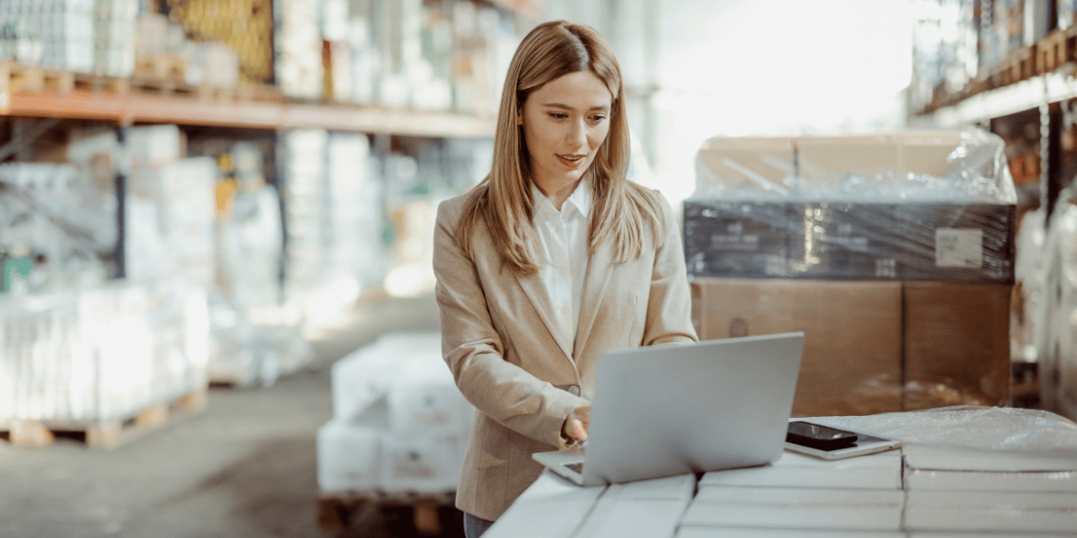 A professional working on a laptop in a retail warehouse, symbolizing AI-powered inventory optimization solutions — balancing stock levels, reducing overstock, and enhancing supply chain efficiency.