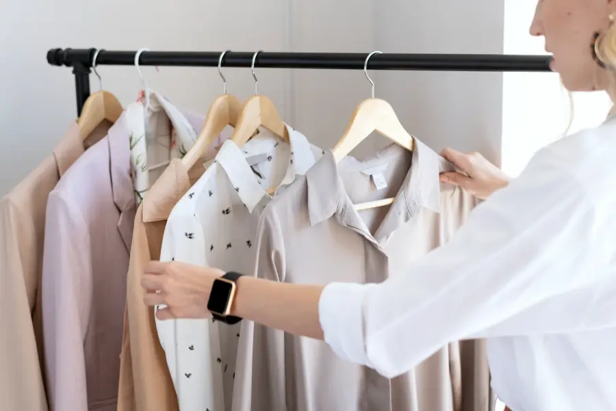 Person reviewing shirts on rack, based on analyzed retail pricing data