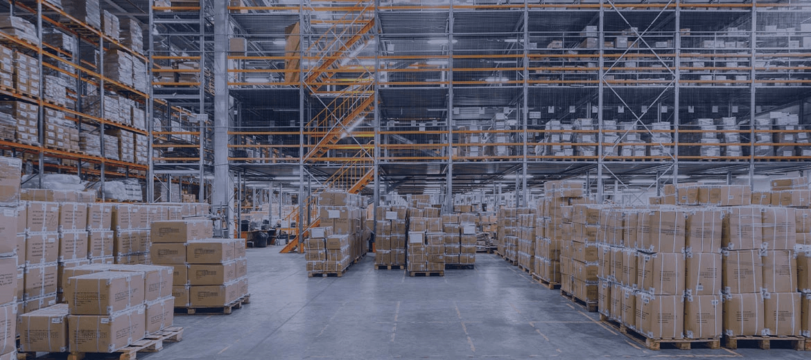 Rows upon rows of pallets filled with boxes in a large warehouse, depicting the problem of excess inventory. This image highlights the need for robust inventory planning software to track stock levels in real-time, optimize inventory across multiple locations, and avoid the financial strain of overstocking.
