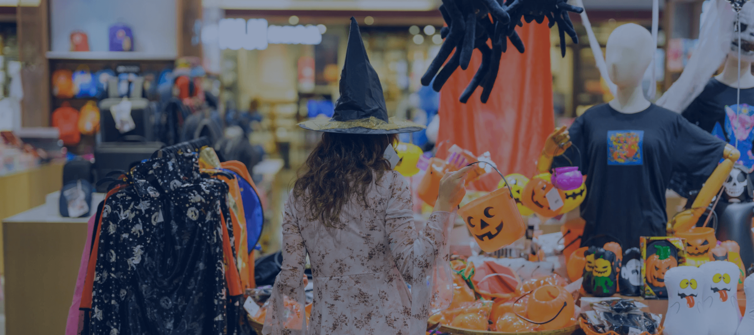 Shopper in a witch hat browsing Halloween-themed retail display, highlighting AI-powered demand forecasting and allocation strategies for seasonal inventory.