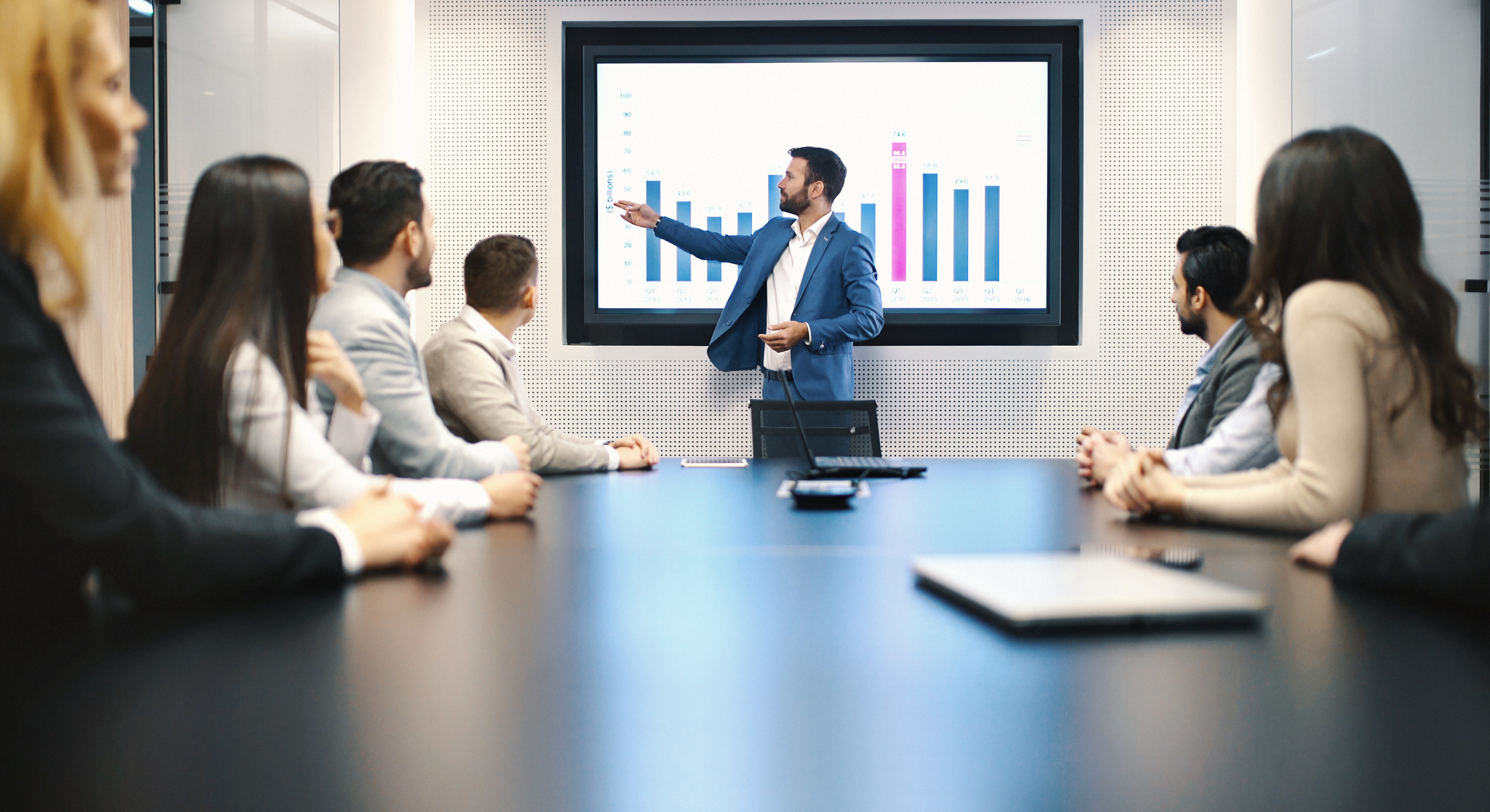 An inventory planner presents sales data and demand forecasts to a team, highlighting inventory levels, cash flow, and supply chain decisions. The meeting focuses on optimizing stock, cutting costs, and effective inventory planning for retail operations.