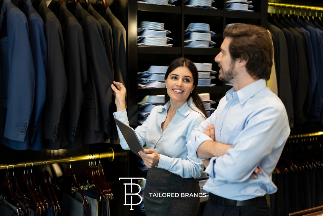 Retail employees discussing tuxedo inventory, representing AI-powered forecasting and inventory optimization at Tailored Brands