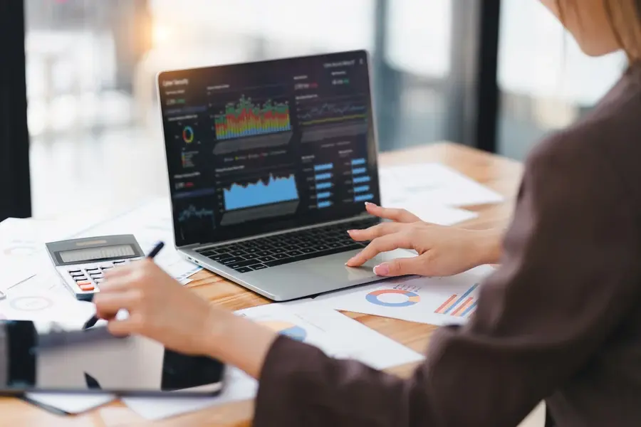 Retail professional analyzing financial data and performance dashboards on a laptop while planning technology investments.