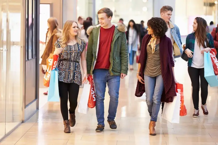 Group of young shoppers walking through a mall, illustrating modern consumer behavior and the importance of an omnichannel experience in today’s retail trends.