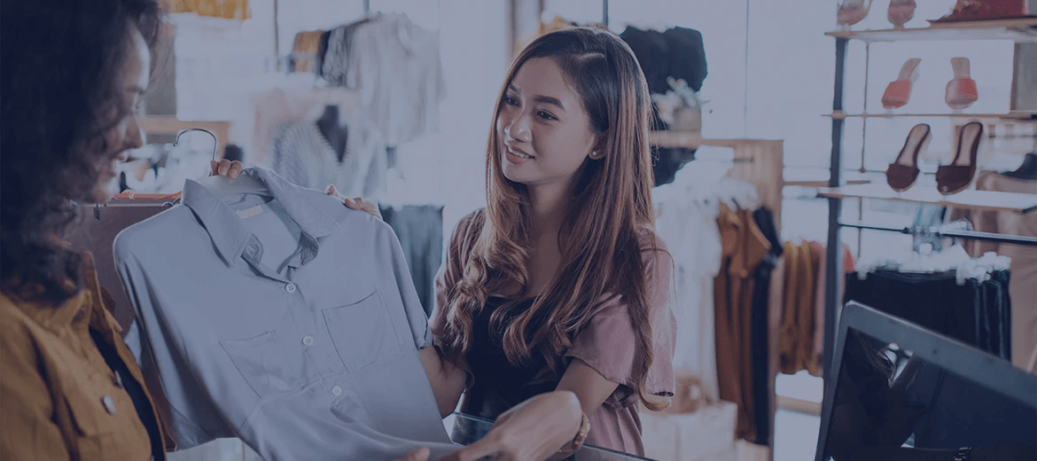 A woman holding a light blue shirt in a clothing store, highlighting a return scenario highlighting the essence of returns forecasting in retail.
