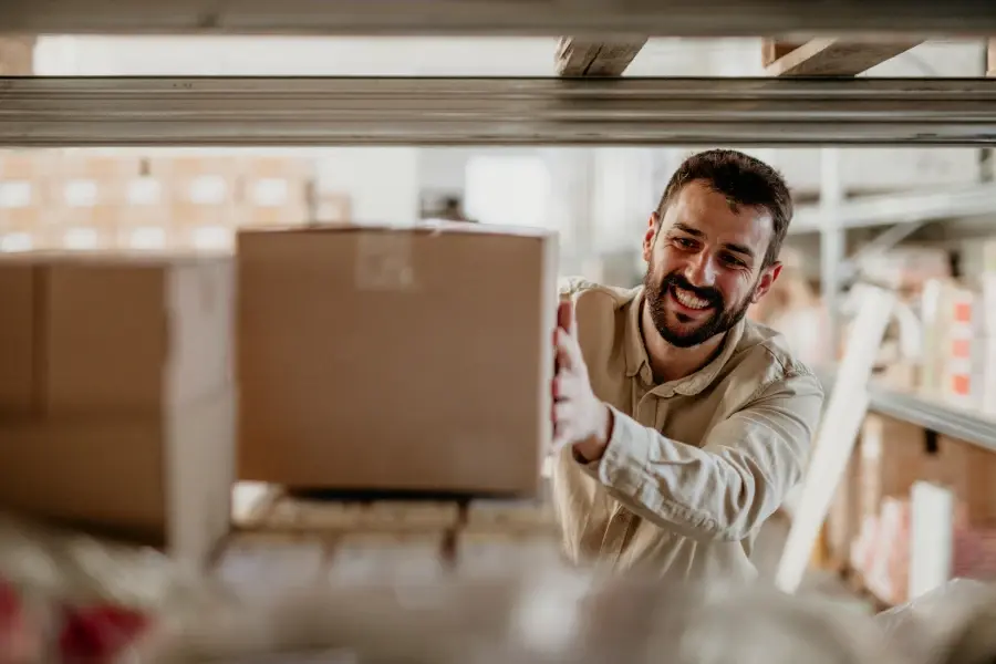 Retail worker placing inventory on warehouse shelves to represent safety stock management.